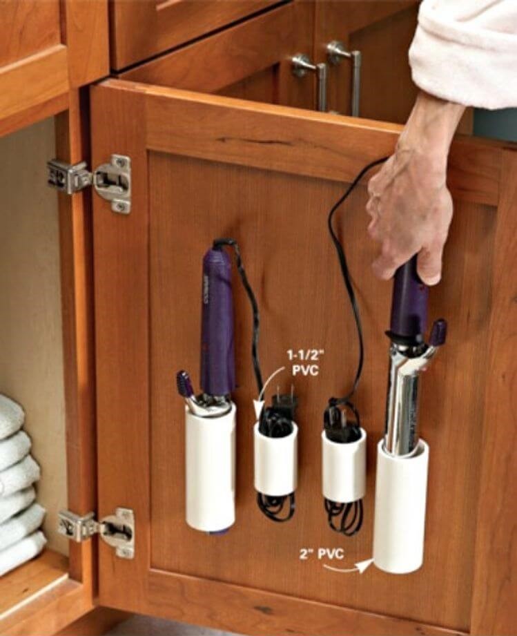 Under bathroom sink storage - pvc pipes attached to bathroom vanity door to store hair styling tools