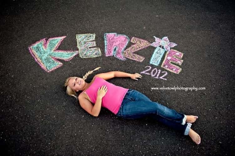 Senior picture ideas for girls - girl lying on sidewalk with her name and graduation year inscribed on sidewalk 