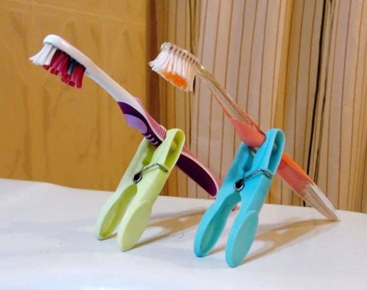 Travel hacks plastic clothespins holding toothbrushes propped on counter