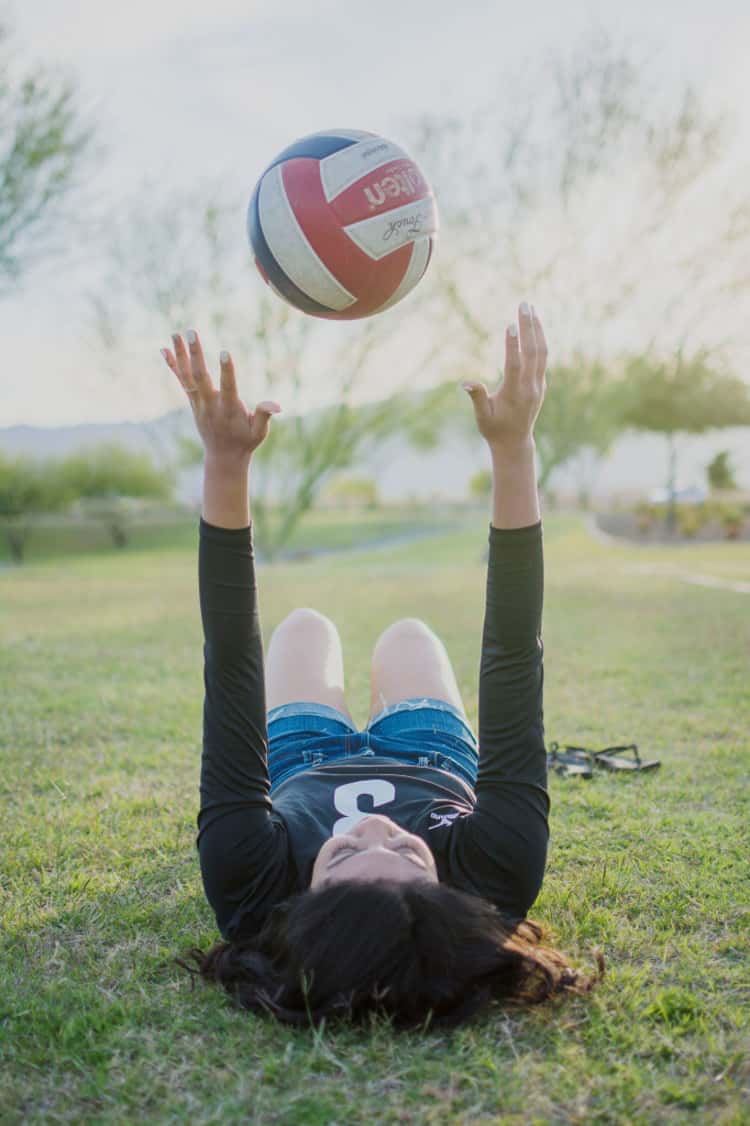 senior picture ideas for girls - girl lying down on her back and while throwing up a volleyball