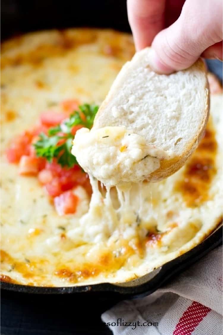 Smoked Mozzarella Fondue Appetizer and a hand dipping a slice of bread in the cheesy mixture