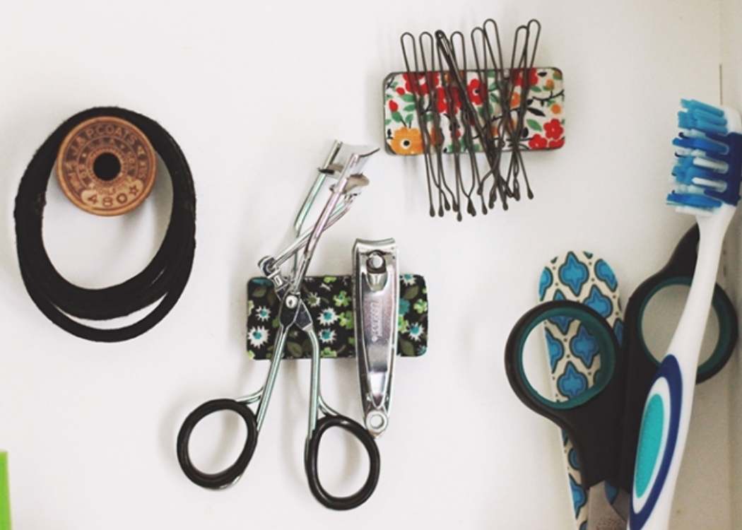 magnets holding hair ties, eyelash curler and nail clippers, bobby pins and scissors