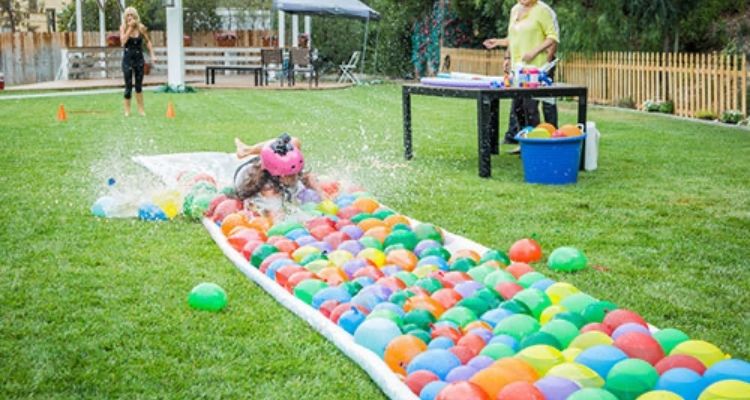 Child sliding on a water balloon slip and slide