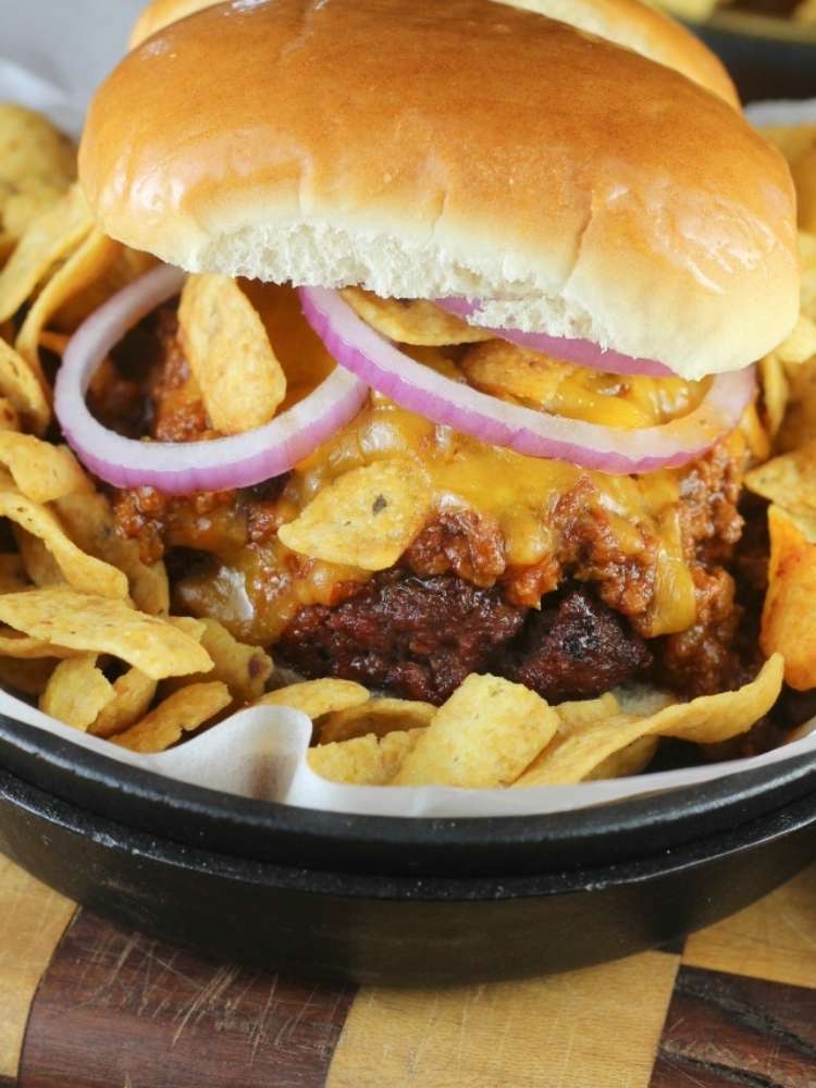 A beef burger topped with barbecue sauce, red onions, cheddar cheese and chili.