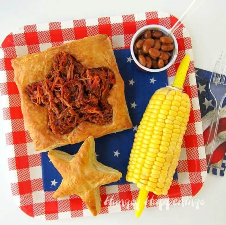 A puff pastry filled with bbq with corn on the cob and baked beans on the side