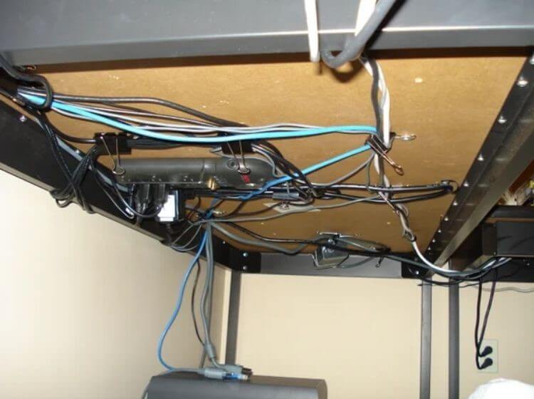 Organize cables by hiding them under a desk using command hooks and binder clips