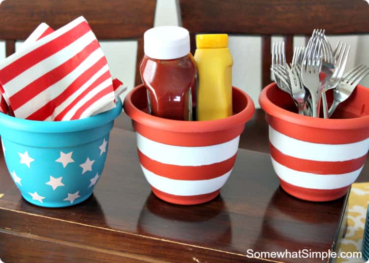 Flower pots painted and decorated differently used as a condiment and utensil station for a 4th of July themed party