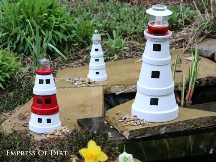 Three DIY flower pot lighthouses placed in a garden 