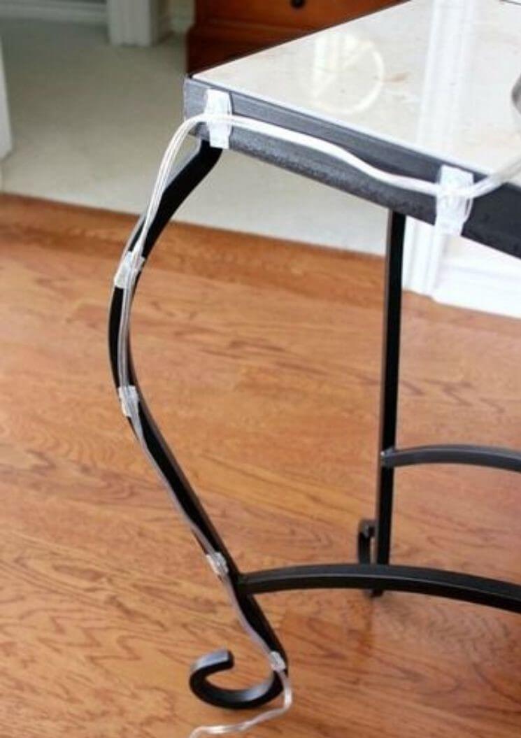 Cable management by attaching a cord to an end table with curved legs using command hooks