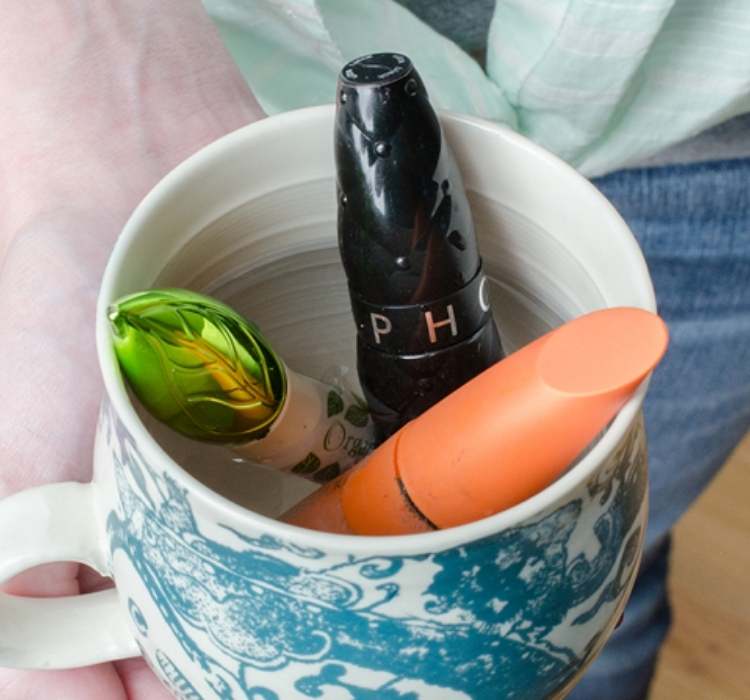 Picture of mascara tubes in cup of warm water to loosen the hardened mascara