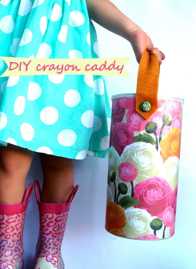 empty oatmeal canister covered in pretty paper with a handle on top used to carry crayons for kids, and a little girl carrying it by the handle