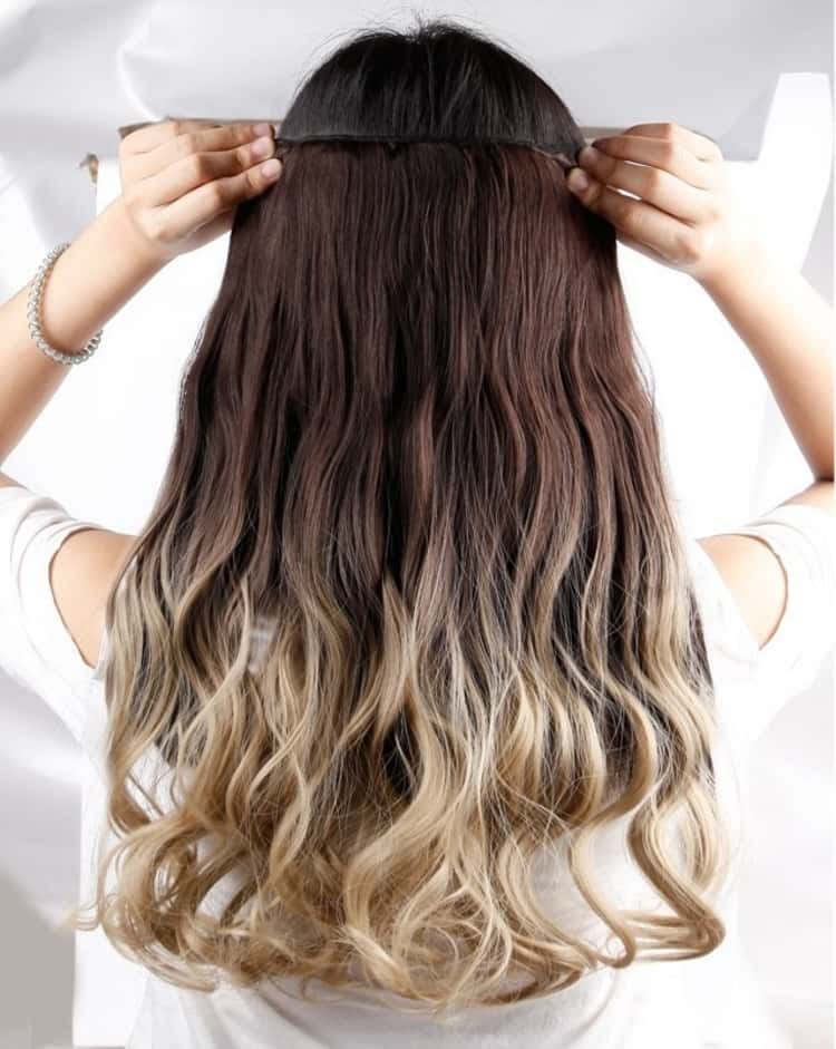 a photo showing a lady adding hair extensions to give more volume to her hait