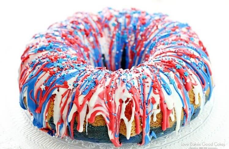 A Bundt shaped cake with red, white, and blue frosting with sprinkles 