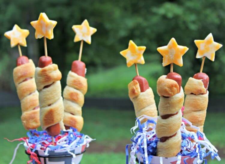 Hot Dogs wrapped in breadstick dough with skewers going through and a star cheese on top - a 4th of July food idea