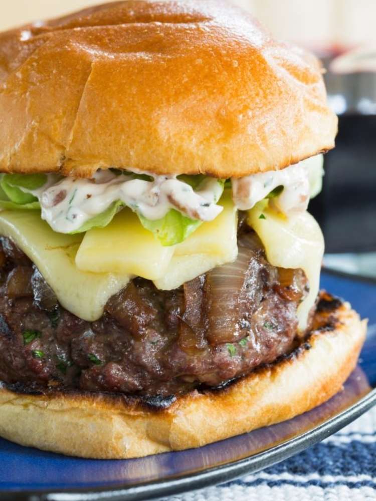 Beef burger topped with grilled onions, cheese, lettuce and a french onion spread.