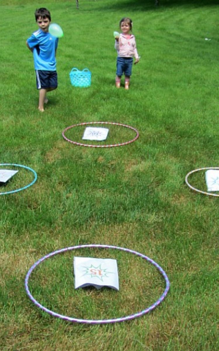 Kids throwing water balloons into hula hoops while doing math