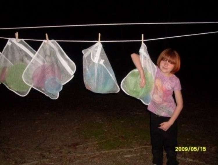 OneCrazyHouse Mesh Laundry Bags child standing in front of mesh bags hanging from a clothes line at night