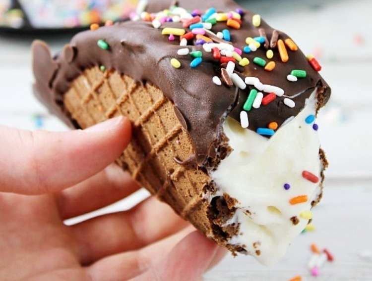 OneCrazyHouse Party Foods Chocotaco made from waffle cone in shape of taco, filled with ice cream and covered on top with chocolate and sprinkles being held by a hand