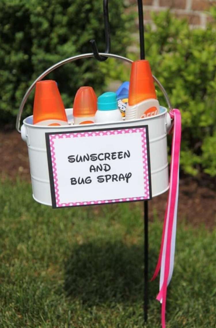 OneCrazyHouse pool storage basket filled with bug sprays and sunscreen hanging in a bukcet on a lawn