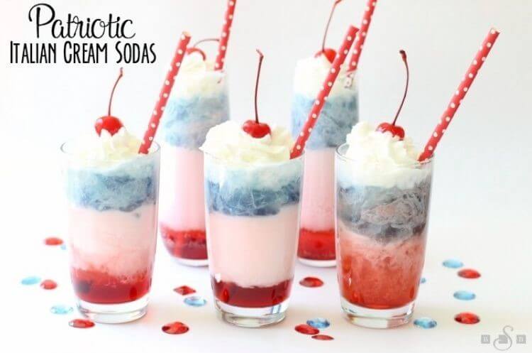 Blueberry and raspberry flavored Italian cream sodas in a clear glass with a red and white polka dot straw, whipped cream, and a cherry on top - 4th of July dessert idea