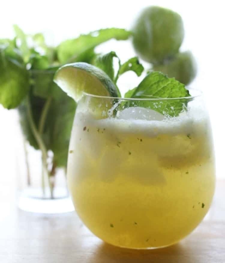 Glass of a pineapple No-Jito garnished with a lemon wedge and mint.
