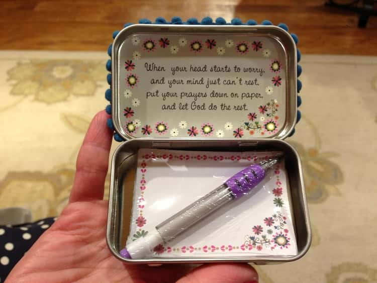 a prayer box made from an empty altoid tin with a pen and paper inside.