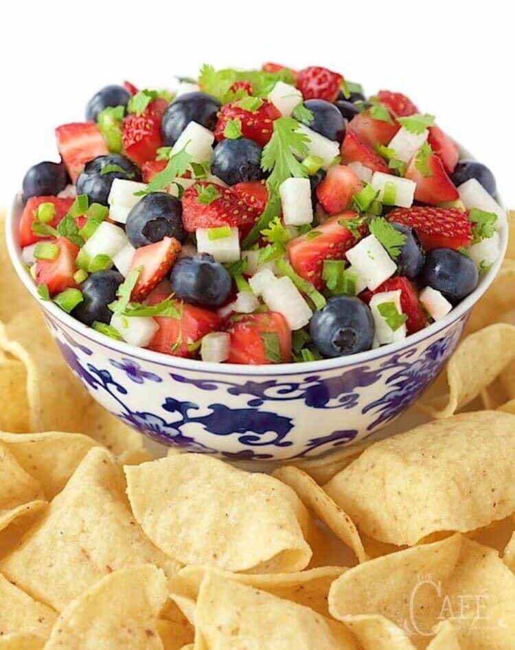 A fruit salad for the 4th of July that contains blueberries, strawberries, and jicama with cinnamon chips surrounding the bowl