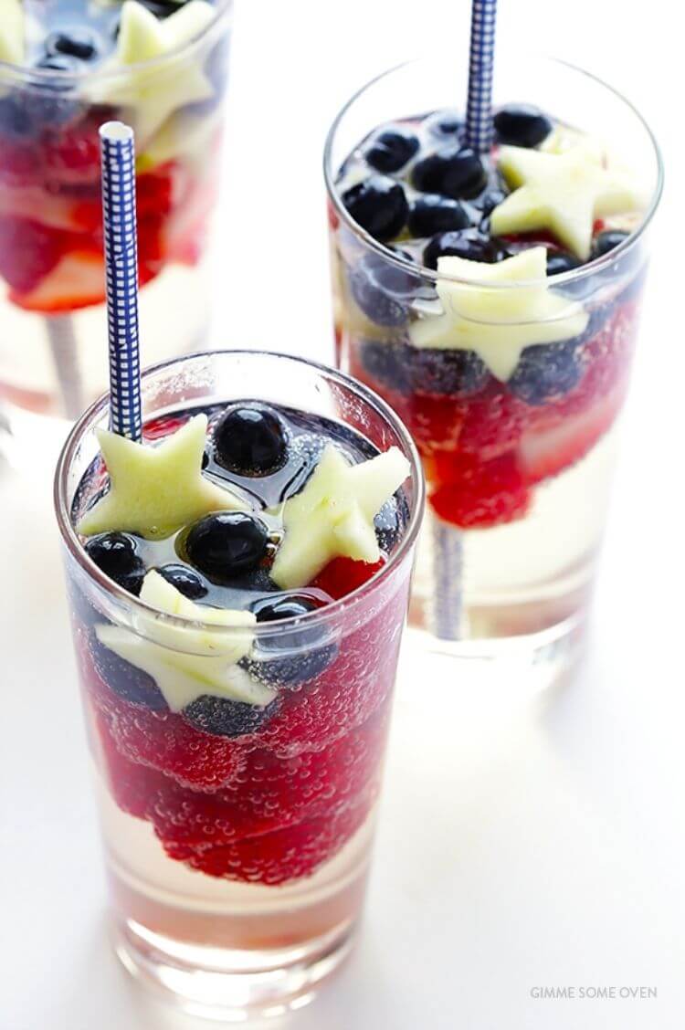 A glass with sangria, fresh fruit, and a blue straw - a 4th of July drink idea