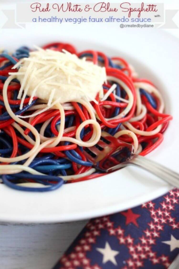 Spaghetti in a bowl that has been dyed red, white, and blue topped with mozzarella and parmesan cheese. 