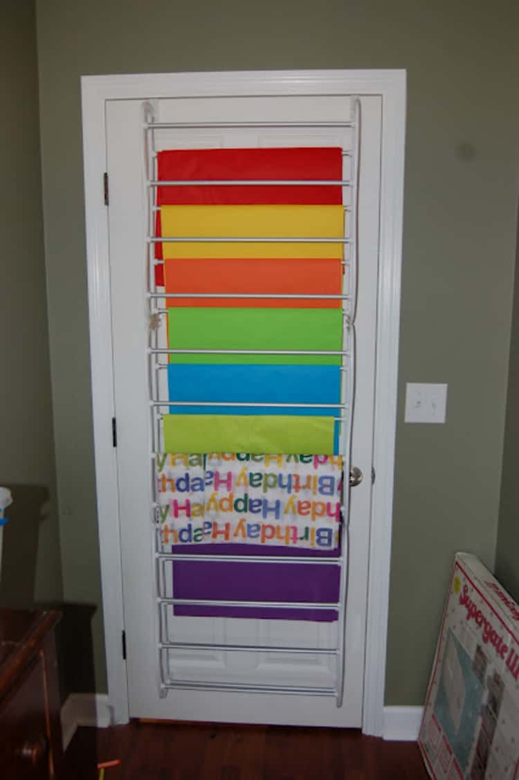 Shoe rack attached to door used to hold gift wrap sheets and tissue paper