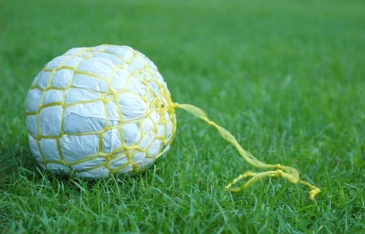 a ball made from plastic bags and a piece of plastic string lying on grass