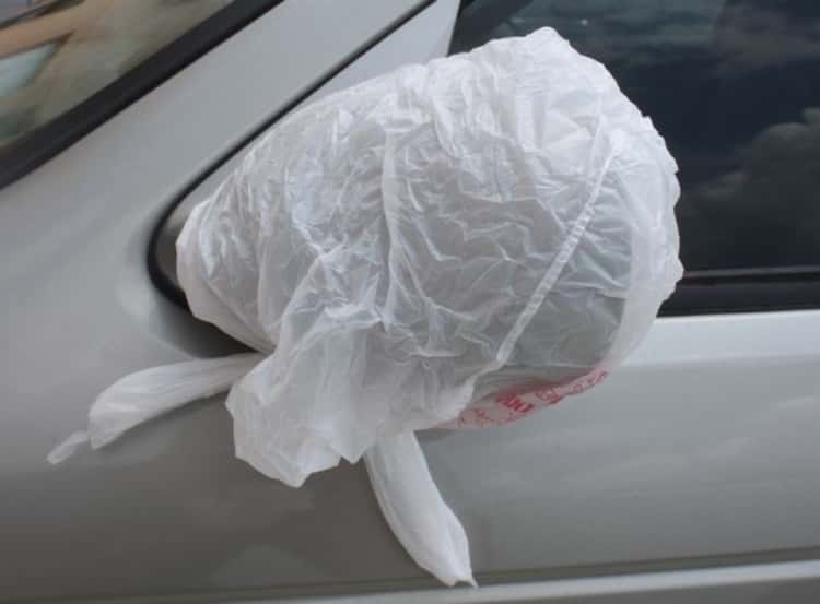 Plastic bag placed over side mirror to protect it from snow build-up on a snowy night