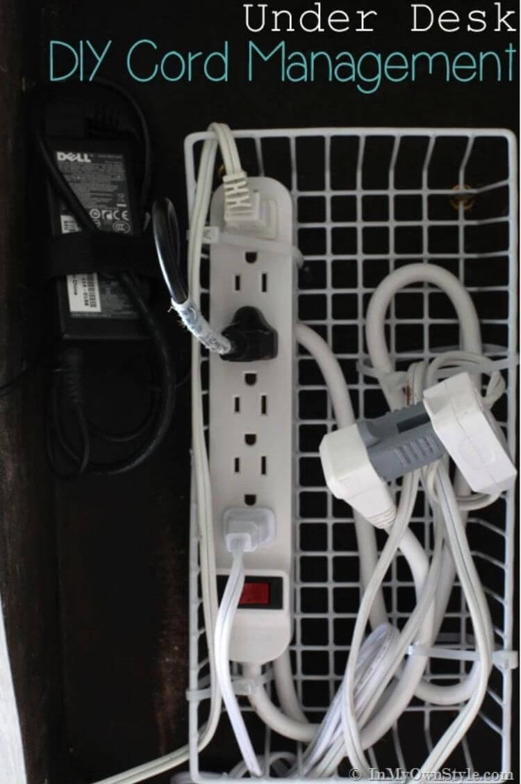 Wire basket hung upside down for cable management. The basket has wires zip tied to it and is hung from the bottom of the desk with hooks.