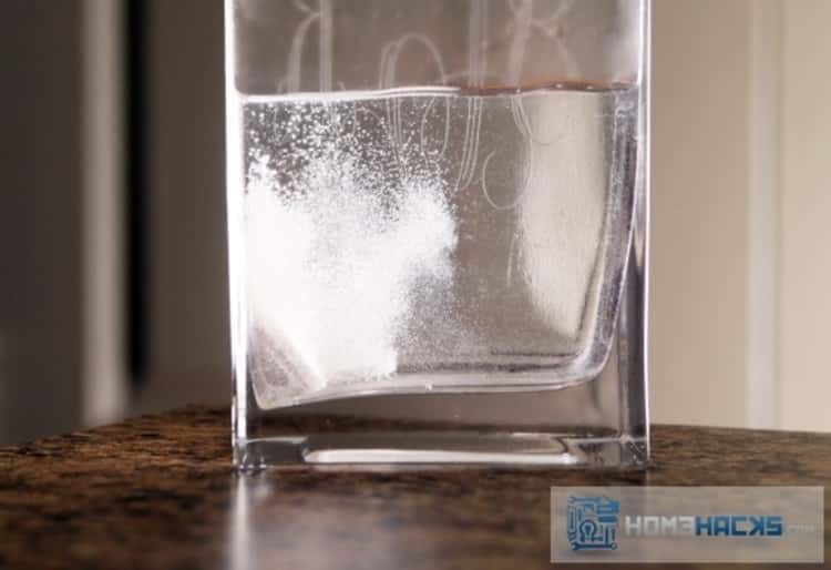 A photo of alka-seltzer fizzing in water placed in a narrow vase to clean it