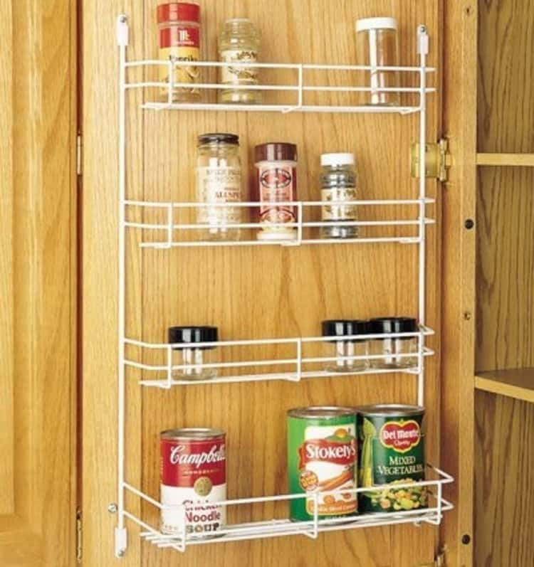 white rack inside a cabinet door holding spices and canned goods