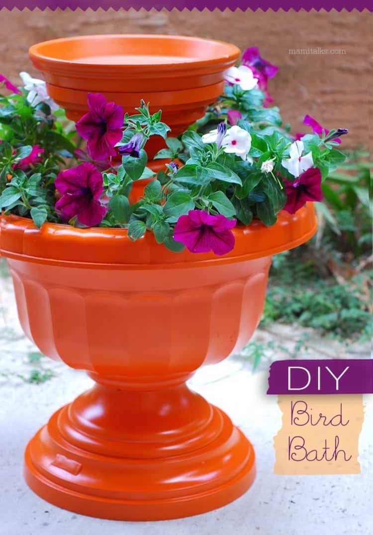 A pretty birdbath made from terra-cotta pots and urns with flowers around it 