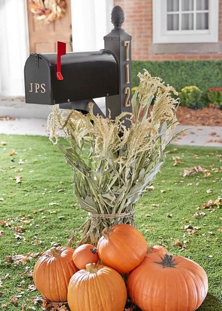 mailbox makeovers - mailbox painted in black with gold accents with some pumpkins at its base