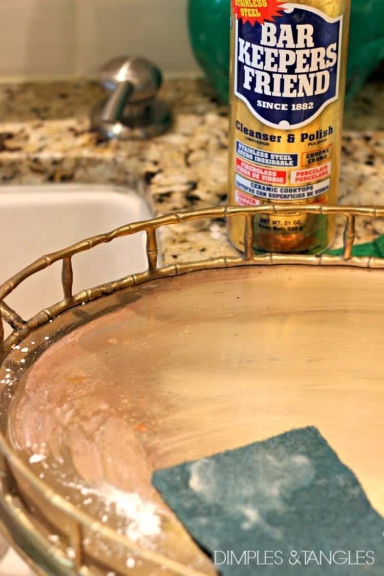 round brass item with a scrubby and bar keepers friend, showing how to strip paint from brass.