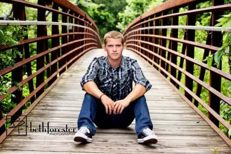 senior picture ideas for guys - guy seated on bridge