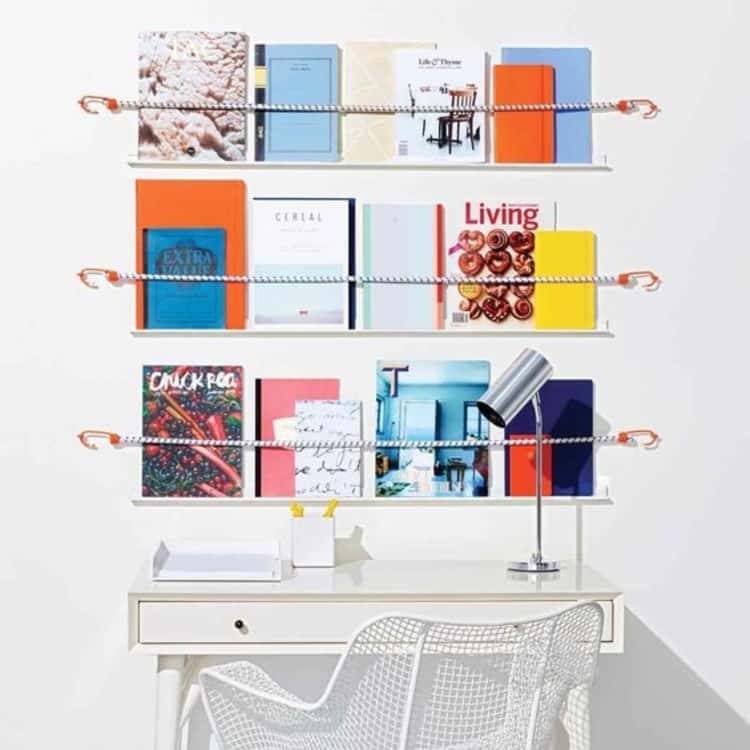 DIY magazine shelf made using bungee cords above a desk