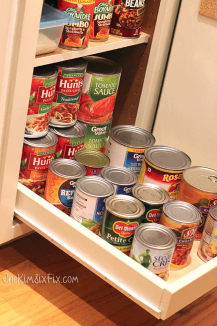 pull out drawer in a cabinet with canned food stored and stacked on it