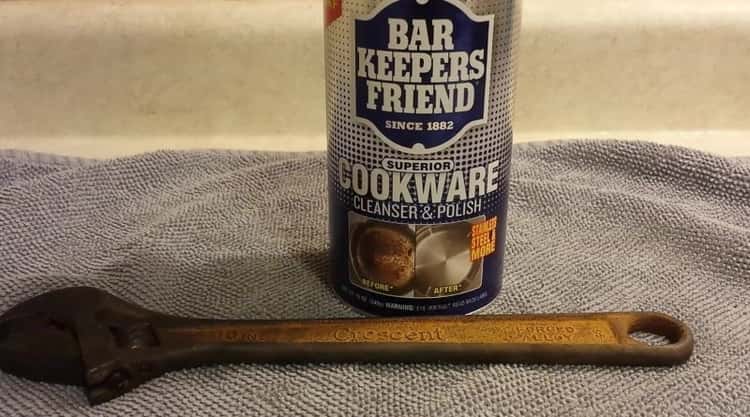 Bar keepers friend sitting on a towel with a rusty wrench laying in front of it