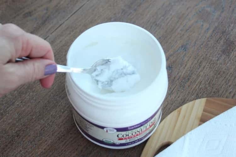 plastic jar of coconut oil with a spoon in the center