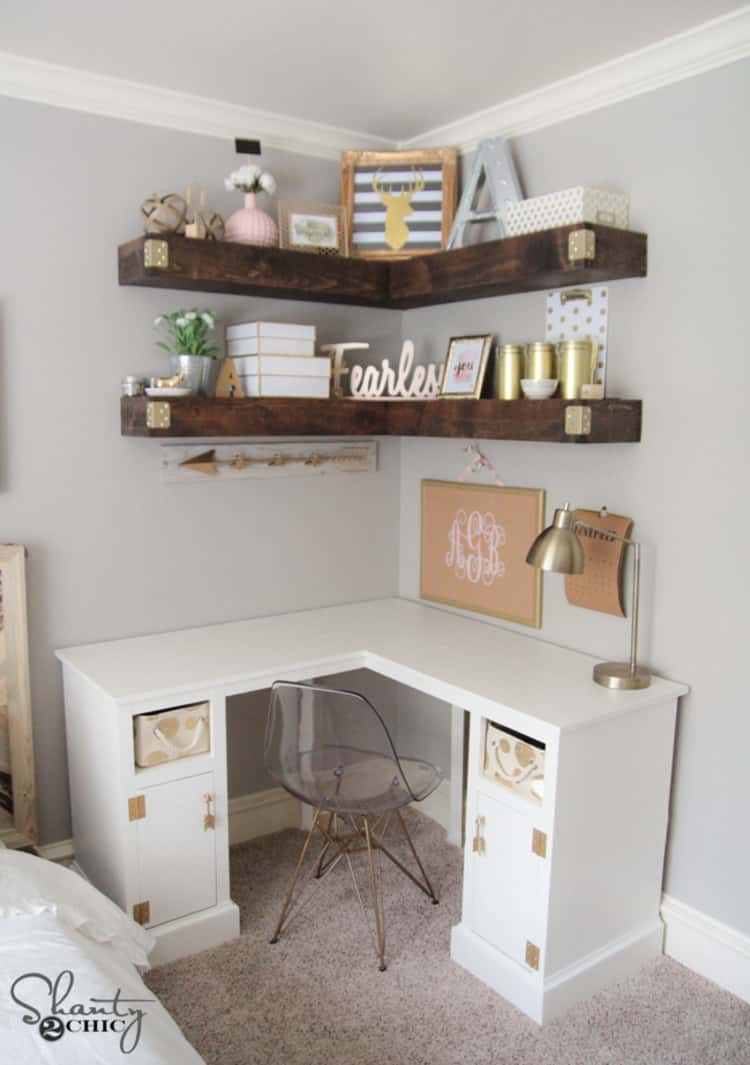 corner desk with a chair and wood shelves above it in the corner