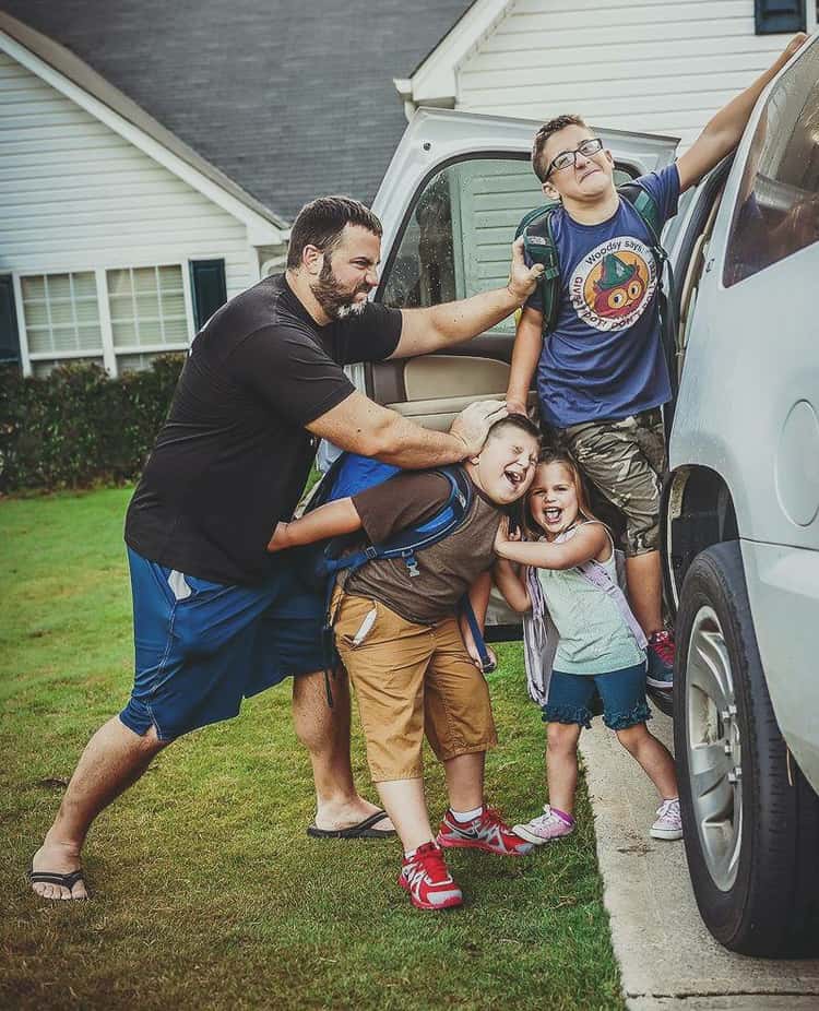 back to school photo ideas - dad pushing 3 kids into car