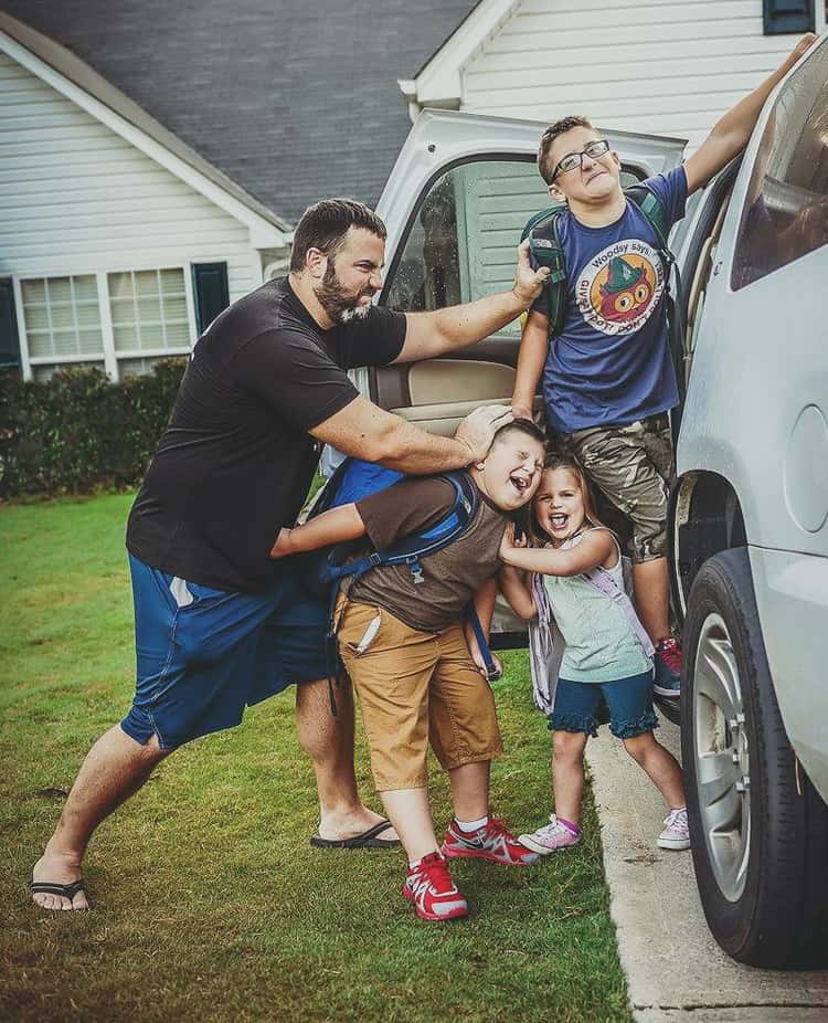 back to school photo ideas - dad pushing 3 kids into car 