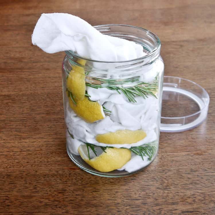 dusting hacks - glass jar containing clear liquid, lemon peels, rosemary springs, and cotton cloths