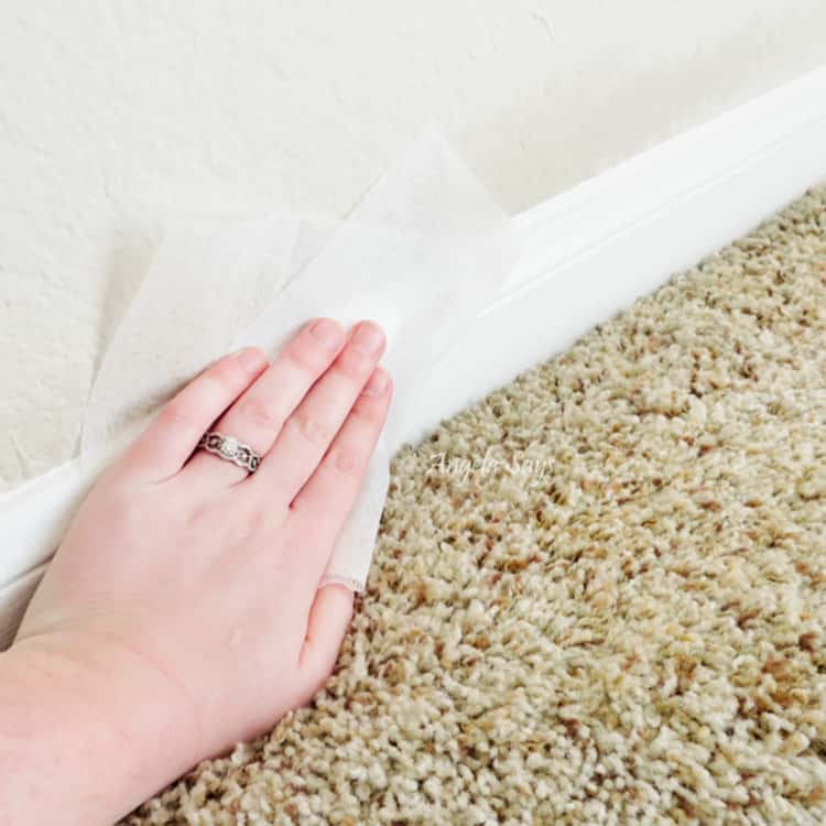 dusting hacks - person wiping baseboard with dryer sheet