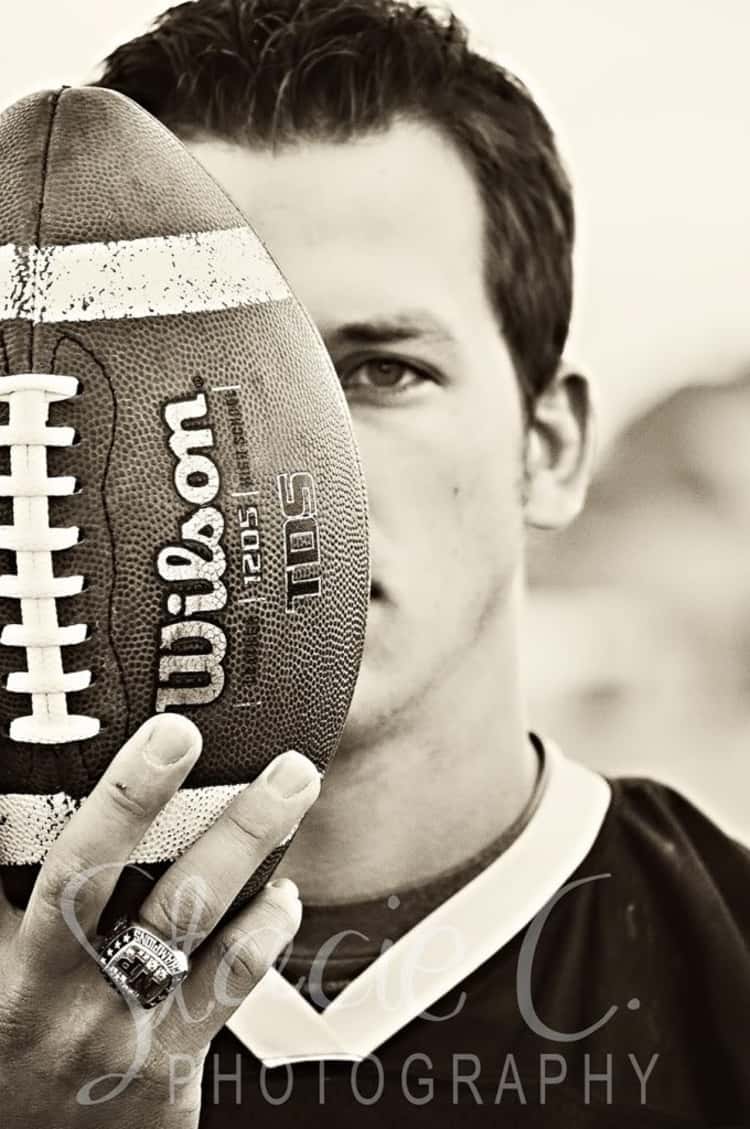 senior picture idea for guys - guy's face partially hidden by a football he's holding upright in front of his face. 