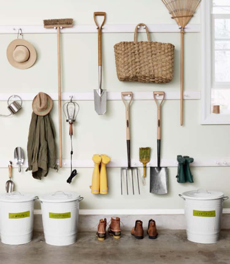 garden tools hanging on pegs on a wall in the garage